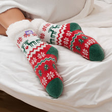 Load image into Gallery viewer, The Foozie™ Christmas Winterland slipper socks, crossed feet on a white bed with the logo tab on the cuff