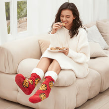 Load image into Gallery viewer, The Foozie™ Cookie Red slipper socks, worn by a woman eating a cookie on the sofa with a plate of cookies